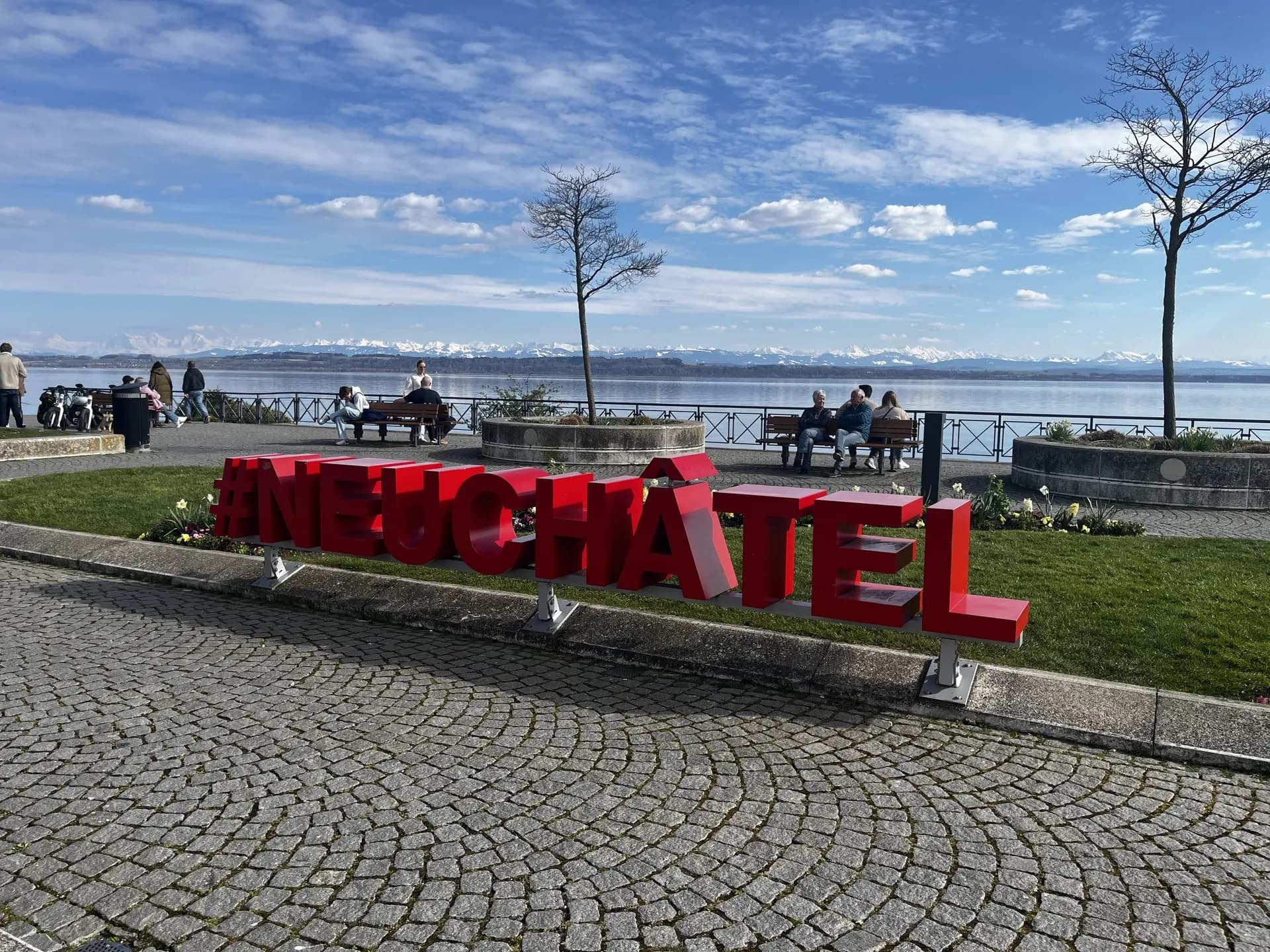 Le lac de Neuchâtel vu depuis la rive, avec les montagnes à l’horizon.